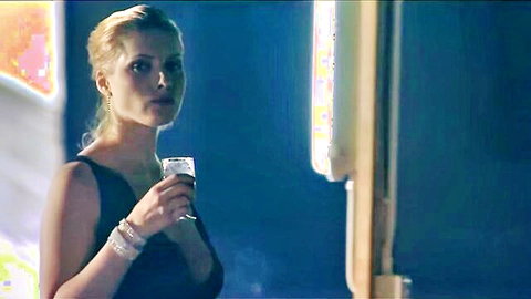 Blonde woman in elegant black dress holding wine glass, seductive gaze