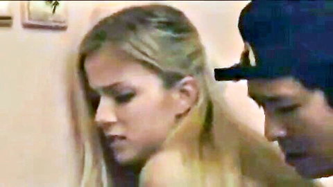 Young blonde with long hair gazes at guy in backwards cap during intimate moment