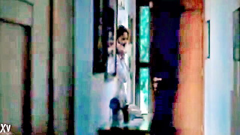 Brunette in tight white dress teasing at door in erotic hallway scene