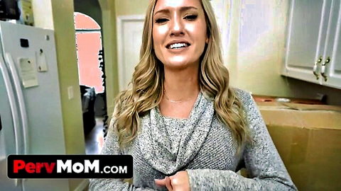 Blonde MILF smiling teasingly in kitchen wearing gray sweater with PervMom watermark