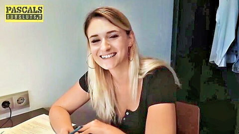 Blonde submissive Melina May smiling in low-cut black top for cuckold scene