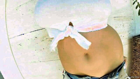 Marina Visconti in tied white crop top and low jeans, teasing toned midriff