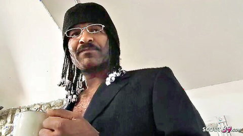 Black man in open suit jacket, beaded dreads, ready for MILF Angela Attison's BBC debut