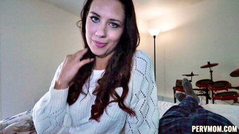 Smiling fair-skinned MILF in white sweater teases on bed with stepson's leg visible POV