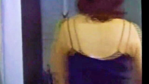 Redhead in yellow strappy top and black bottoms teasing from behind in bedroom