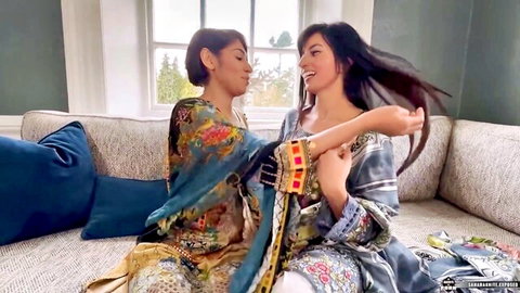 Two sexy South Asian brunettes in colorful shalwar kameez teasing intimately on couch