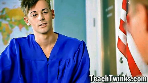 Young twink in blue graduation gown smirks seductively in classroom