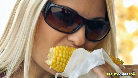 Blonde babe in big sunglasses bites juicy corn cob like a cock outdoors