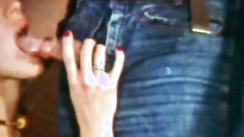 Woman with red nails grips thick hard cock pulled from unzipped blue jeans with mouth open to suck.