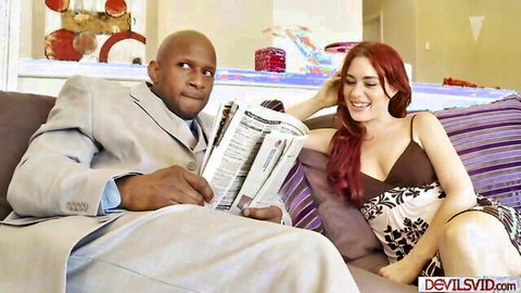 Interracial redhead in cleavage top smiles at suited black DILF stepdad reading newspaper on couch