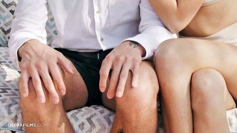 Skinny fair e-girl hugs boyfriend intimately while he grips thighs in black shorts poolside