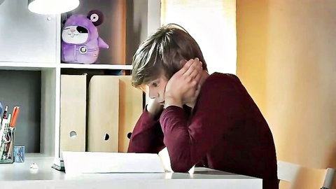 Thoughtful young man with hands on face studying at desk in cozy room