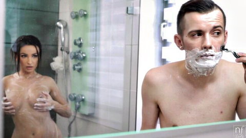 Wet naked brunette squeezes her medium natural tits in steamy shower while her man shaves in mirror