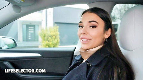 Young tanned Latina brunette with long hair smiling seductively in luxury car passenger seat