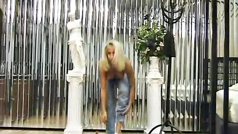 Blonde babe bends over topless exposing huge tits in luxurious room