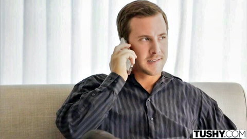 Handsome man in striped shirt talking on phone while seated on couch
