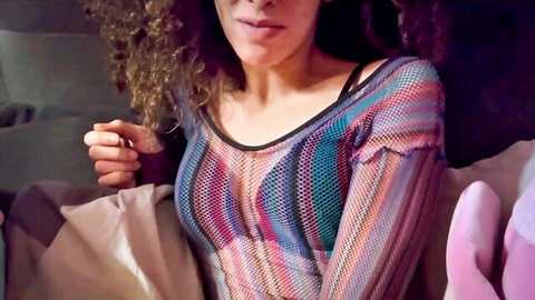 Curly haired ebony babe in sheer colorful mesh top exposing perky tits on bed