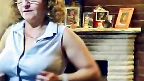 Mature busty woman in open blouse teasing cleavage on webcam