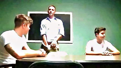 Gay teacher stands before two twinks sitting at desk in classroom