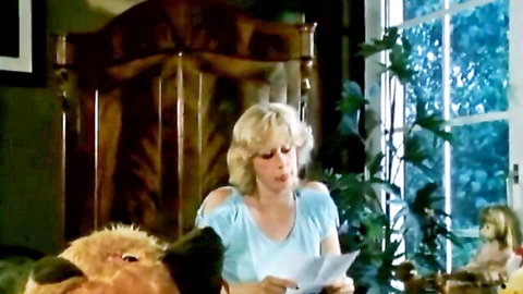 Blonde teen in casual top holds letter on bed, initiation scene preview