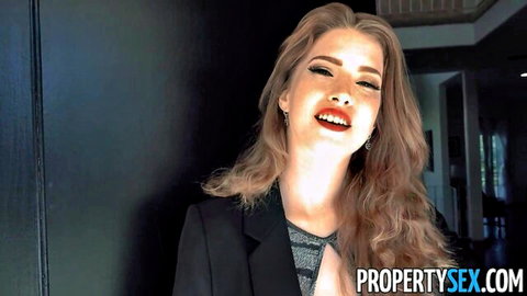 Blonde real estate agent with massive tits smiling in black blazer, ready for hot deal
