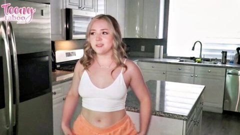 Eva Nyx blonde teen in white crop top and orange shorts posing in kitchen