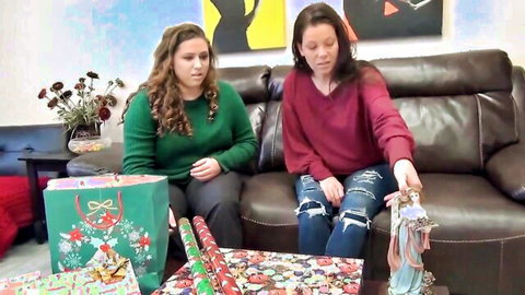 Two BBW brunettes unwrapping gifts on couch in holiday scene