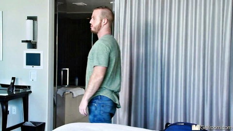 Hot bearded stud in t-shirt and jeans, standing by shower in hotel room