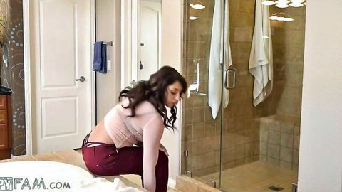 Curvy stepmom in sheer top and low red pants, bending over in steamy bathroom tease