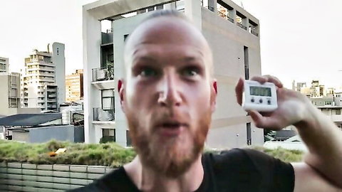 Bald bearded man on hotel rooftop holding timer, teasing swinger couple adventures