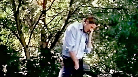 Mature man in white shirt on phone in wooded garden - classic XXX teaser