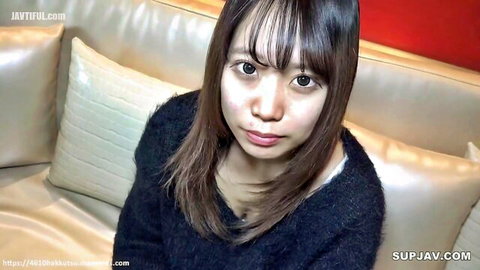 Sexy Asian woman with bangs in black sweater, intimate gaze on couch