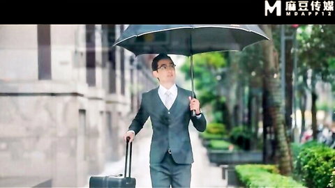 Asian businessman in suit walking with umbrella and suitcase on city street