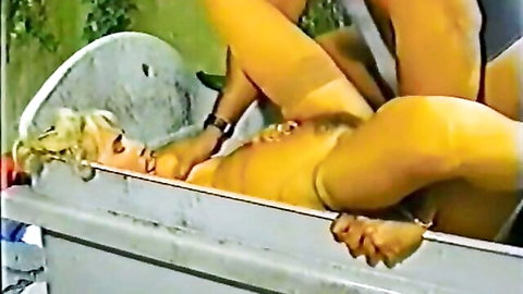 Wet blonde MILF lies in tub legs spread wide exposing shaved pussy gripped by hands