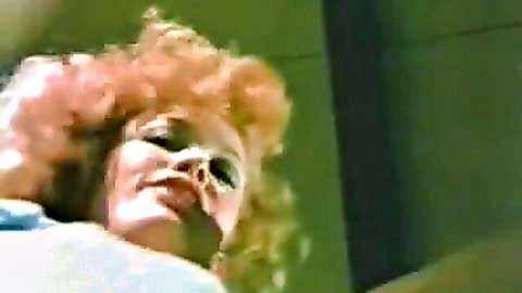 Retro ginger woman with curly red hair and heavy makeup in close-up oral tease