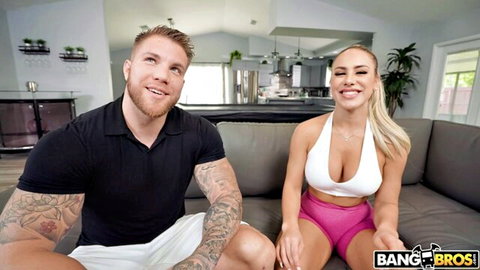 Busty blonde babe with fake tits smiles with muscular tattooed stud on couch