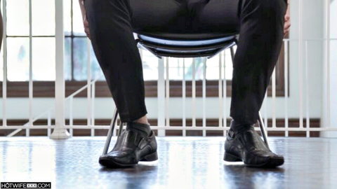 Man in tight black pants sitting with legs spread wide on curved office chair