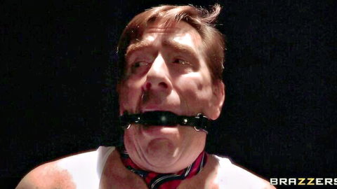 Muscular man gagged with black ball gag muzzle in intense BDSM scene