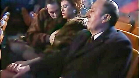 Busty redhead mature woman in fur coat groped by two older men in public theater seats
