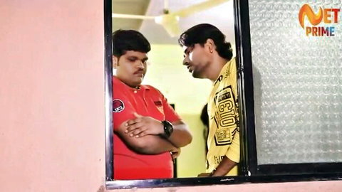 Two Indian men in casual shirts talking intensely by a pink window wall