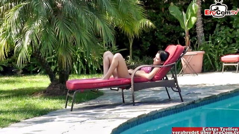 Petite Asian beauty in pink bikini lounging poolside