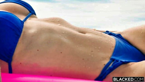 Malena in blue bikini lounging wet on pool float, toned abs
