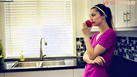 Lucy in pink top biting red apple, kitchen tease for squirt solo