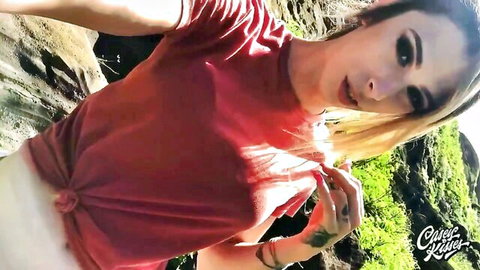 Blonde TS woman in red top and white skirt posing seductively outdoors