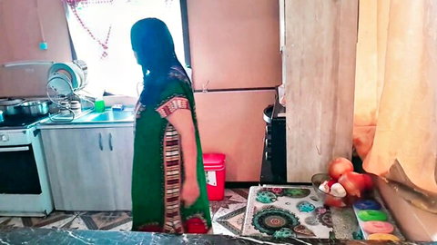 Indian housewife in green saree stands in kitchen showing curvy big ass from side view