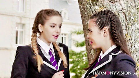 Two sexy schoolgirls in tight uniforms chatting flirtatiously outdoors by tree