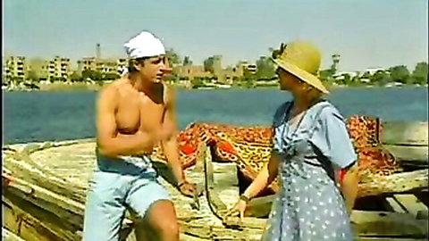 Vintage Egyptian boat scene: Shirtless hunk chats with busty maid and friend on Nile