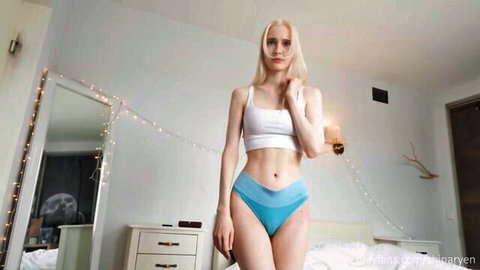 Skinny blonde babe in white crop top and skimpy blue panties posing in bedroom