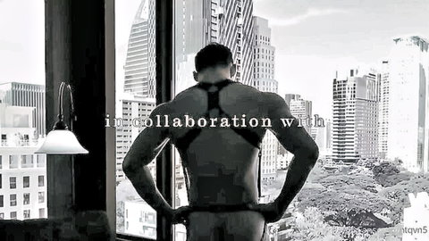 Muscular stud in leather BDSM harness exposes bare ass overlooking Bangkok skyline