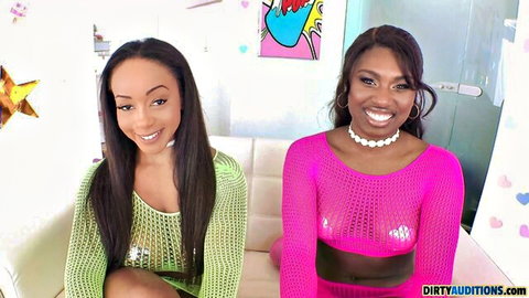 Lily Starfire and Tessa Thomas in sexy mesh tops, smiling on couch